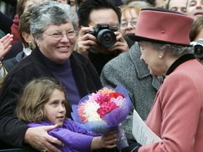 Queen Elizabeth II accepts flowers from Katie Holness, 8, and her grandmother Amy after a morning church service in Victoria, B.C. on Sunday Oct. 6, 2002.