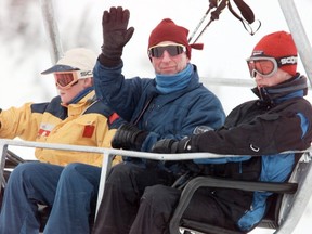 Prince Charles waves to the media and onlookers gathered at the site of the photo op during their skiing vacation here while his sons Prince Harry (left) and Prince William (right) ride the red chair with him on Whistler Mountain. (Nick Didlick/PNG)
