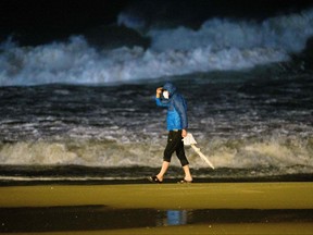 A man walks past waves crashing on the shoreline as Typhoon Hinnamnor approaches in Busan, South Korea on Sept. 5, 2022.
