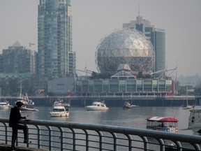 Smoke obscures condo towers and Science World as people stands on the False Creek seawall in Vancouver, on Sunday, September 11, 2022. Environment Canada issued an air quality advisory for Metro Vancouver and the Fraser Valley advising people to avoid the outdoors due to wildfires burning near Chilliwack, Hope and in the U.S.