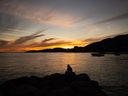 A man is silhouetted as he sits on rocks while watching the sunset at Ambleside Beach in West Vancouver, B.C., Saturday, Aug. 13, 2022. Forests Minister Katrine Conroy says it's been a below average wildfire season so far this year in British Columbia, but high fire risks are forecast for September.