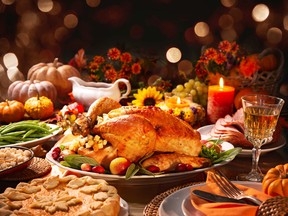 Thanksgiving dinner. Roasted turkey garnished with cranberries on a rustic style table decoraded with pumpkins, vegetables, pie, flowers, and candles