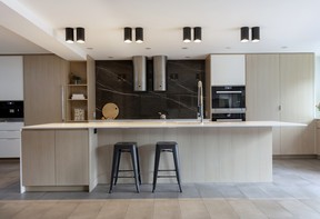 In the middle of the main floor, the kitchen features clean-lined modern cabinetry in oak and white. Cylindrical light fixtures and cylinder-style Faber oven hoods echo tubular shapes found in the family's classic-modern Le Corbusier and Breuer furniture pieces.