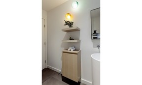 A petite powder room on the home's main floor got a space-saving makeover, including shallow storage, a cylindrical pedestal sink and wall-mounted Bocci lights.