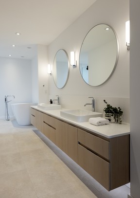 As part of the renovation, the ensuite bath expanded, borrowing floor space from an oversize primary bedroom. This allowed Parvaresh to fit in a floating oak vanity with double sinks, soaker tub and large shower.
