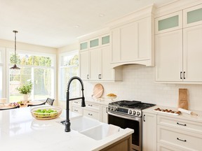 Yes, a white kitchen can be warm and inviting, thanks to complementary shades of off-white paint on the walls and cabinets.