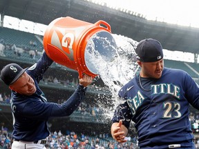 Jarred Kelenic #10 douses Ty France #23 of the Seattle Mariners with water after France's walk-off single to beat Detroit Tigers 5-4 at T-Mobile Park on October 05, 2022 in Seattle, Washington.