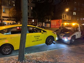 Un camión aleja una camioneta amarilla de la escena de un incidente policial en Main Street, cerca de National Avenue, la noche del 6 de octubre de 2022.  Un sospechoso de robo a un banco se había atrincherado en un taxi esa misma noche.