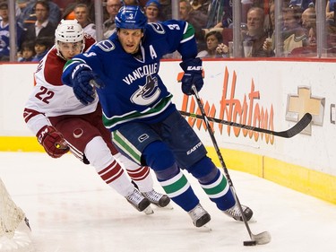 Kevin Bieksa #3 of the Vancouver Canucks picks up the loose puck while pressured by Craig Cunningham #22 of the Arizona Coyotes in NHL action on April 9, 2015 at Rogers Arena in Vancouver, British Columbia, Canada.