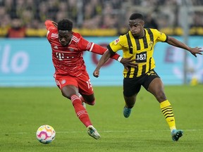 Bayern's Alphonso Davies vies for the ball with Dortmund's Youssoufa Moukoko, right, during the German Bundesliga soccer match between Borussia Dortmund and Bayern Munich in Dortmund, Germany, Saturday, Oct. 8, 2022.
