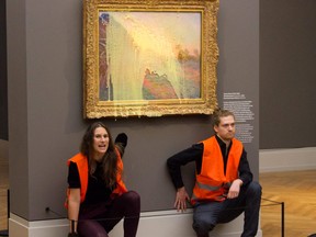 This handout picture released on October 23, 2022 by climate movement "Last Generation" shows activists of the group being glued underneath the painting "Les Meules" by French artist Claude Monet after pouring mashed potatoes on the artwork in the Barberini museum in Potsdam on October 23, 2022.
