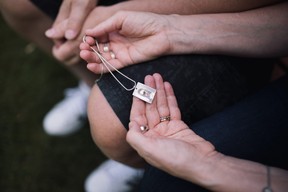 Hollie Hall holding a pendant with Lily's finger print created by Canuck Place's recreation therapy team