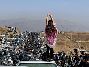 An image posted on Twitter on Oct. 26, 2022, shows an unveiled woman standing on top of a vehicle as thousands make their way towards Aichi cemetery in Saqez, Mahsa Amini's hometown in the western Iranian province of Kurdistan, to mark 40 days since her death, defying heightened security measures as part of a bloody crackdown on protests against the regime.