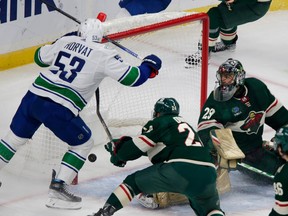 Vancouver Canucks center Bo Horvat (53) scores a goal on Minnesota Wild goaltender Marc-Andre Fleury (29) with Matt Dumba (24) helping defend during the first period of an NHL hockey game Thursday, Oct. 20, 2022 in St. Paul, Minn.