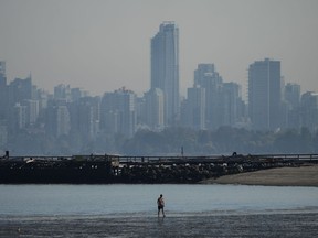 A man walks in the water off Locarno Beach during a stretch of unseasonably warm weather, in Vancouver, B.C., Thursday, Oct. 6, 2022.