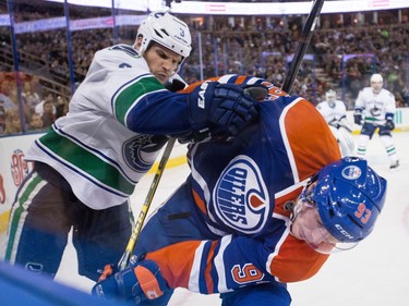Edmonton centre Ryan Nugent-Hopkins (93) is checked by Vancouver defenceman Kevin Bieksa (3) during the third period of a NHL hockey game between the Edmonton Oilers and the Vancouver Canucks at Rexall Place in Edmonton, Alta., on Saturday, Nov. 1, 2014. The Canucks won 3-2.