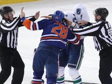 Edmonton forward Ryan Jones (28) fights Vancouver defenceman Kevin Bieksa (3) as the Edmonton Oilers play the Vancouver Canucks during the first period of a NHL hockey game at Rexall Place in Edmonton, Alta., on Tuesday, Jan. 21, 2014.