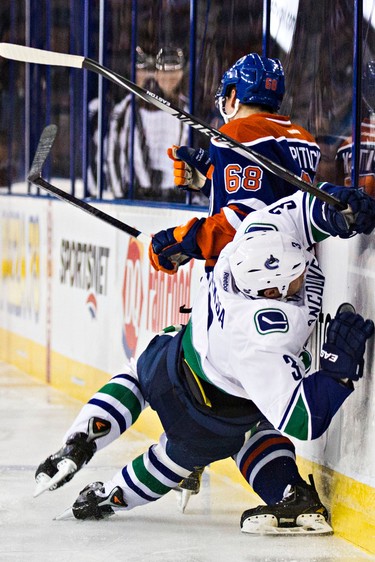 Edmonton's Tyler Pitlick (68) is hit by Vancouver's Kevin Bieksa (3) during the Edmonton Oilers' NHL pre-season hockey game against the Vancouver Canucks at Rexall Place in Edmonton, Alta., on Thursday, Oct. 2, 2014.
