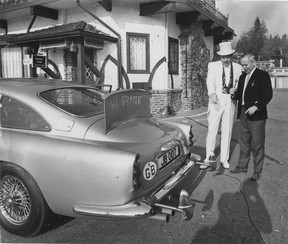 Frank Baker checks out the James Bond Aston Martin DB5 he purchased when it arrived at his West Vancouver restaurant The Attic on Nov. 18, 1969. Someone has written “Hi Frank” in chalk on the bullet deflector shield behind the rear windshield. Bill Cunningham/Province