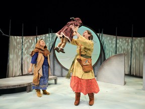 The character of Grandmother Moon watches with glee while the character Wapam hoists a puppet child in Frozen River, playing at the Waterfront Theatre on Granville Island.