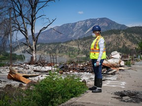 Denise O'Connor stands on the sidewalk in front of the remains of her home that burned down when a wildfire destroyed the village in 2021, in Lytton on Wednesday, June 15, 2022.