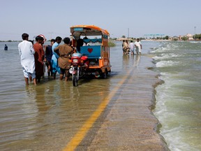 FILE PHOTO: Displaced people stand on flooded highway, following rains and floods during the monsoon season in Sehwan, Pakistan, September 16, 2022.