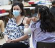 RN Grace Oloresisisimo gives Lillian May an injection at a flu and COVID vaccination clinic at UBC in Vancouver, BC on Wednesday, October 12, 2022.