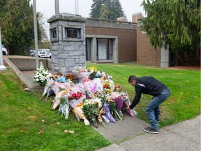 A man lays flowers for fallen RCMP member Const. Shaelyn Yang at the Burnaby, BC RCMP detachment Thursday, October 20, 2022. Const. Yang was killed in the line-of-duty October 18 in Broadview Park while helping a city by-law officer check-on a homeless man living in the park.(Photo by Jason Payne/ PNG)