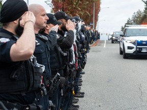 Police and emergency services personnel and civilians line the street outside the B.C. RCMP detachment in Surrey to pay their respects to Const. Shaelyn Yang as her body passed by in procession on Friday, October 21.