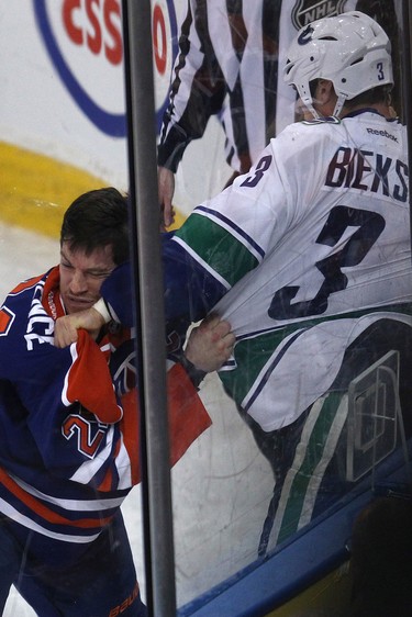 The Edmonton Oilers' Andrew Ference (21) fights the Vancouver Canucks' Kevin Bieksa (3) during first period NHL action at Rexall Place, in Edmonton Alta., on Wednesday Nov. 19, 2014.