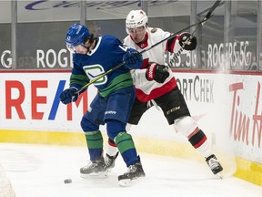 Quinn Hughes (left) and Josh Norris, battling for the puck during an April 2021 NHL game at Rogers Arena, are longtime friends who won't hook up again at the Canadian Tire Centre on Tuesday — the Sens' Norris is sidelined long term with a torn shoulder labrum.