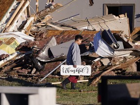 Logan Johnson, 11, carries a sign that reads "Thankful" after he recovered it from his family's destroyed home after a tornado hit in Powderly, Texas, Nov. 5, 2022.