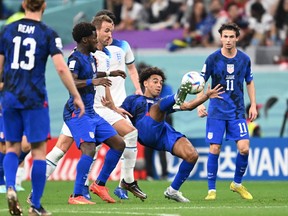 USA's midfielder Tyler Adams (2ndR) kicks the ball past England's forward Harry Kane during their match.