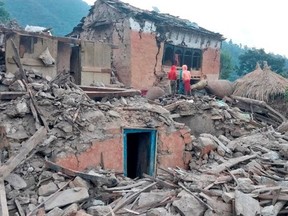 People stand outside the ruins of collapsed houses after an earthquake struck early Wednesday, in the western district of Doti, Nepal Nov. 9, 2022.