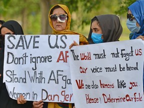 Afghans hold placards as they gather to demand help from the United Nations High Commissioner for Refugees who was visiting Islamabad, Pakistan, on May 12, 2022.