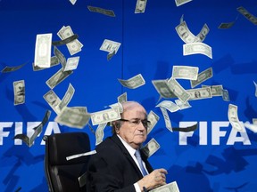 In this file photo taken on July 20, 2015, FIFA president Sepp Blatter sees fake dollar bills thrown around him by British comedians during a press conference at the FIFA world bodies headquarters in Zurich. flying.