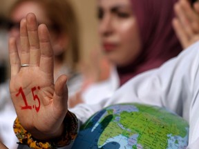 An activist with paint on her hand reading "1.5 degrees", referring to demands to limit global temperature rise to 1.5 degrees Celsius compared to pre-industrial levels, stands holding a globe during a demonstration at the COP27 climate conference in Egypton November 16, 2022.