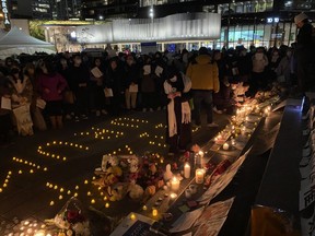 People light candle at a vigil in front of the Vancouver Art Gallery for the victims of an apartment fire in the far western city of Urumqi, China, during a protest in Vancouver on Sunday, Nov. 27, 2022.