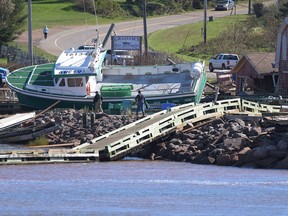 A lobster boat stranded on rocks on the quay of Stanley Bridge, PEI, after post-tropical storm Fiona, September 25, 2022. The tide is rising, the sand is shifting, and the coastline is crumbling. Canada's coastal regions are wondering what the future holds as research warns of rising sea levels and accelerating erosion caused by climate change.