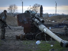 A Ukrainian soldier inspects a damaged Russian cannon in the recently retaken village Chornobaivka near Kherson, Ukraine, Tuesday, Nov. 15, 2022.