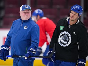 Former Vancouver Canucks defenceman Kevin Bieksa, right, who signed a one-day contract with the NHL hockey team to officially retire, talks with head coach Bruce Boudreau as he skates at the start of practice, in Vancouver, on Thursday, November 3, 2022. Bieksa will be honoured by the team with a retirement celebration prior to their game against the Anaheim Ducks on Thursday night.