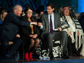 John Horgan fist-bumps David Eby after Eby is sworn in as B.C. premier during a ceremony at the Musqueam community centre in Vancouver