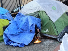 A resident of the Downtown Eastside tries to keep warm outside his tent on Wednesday.