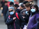 Masked commuters wait for their bus in downtown Vancouver on Monday.