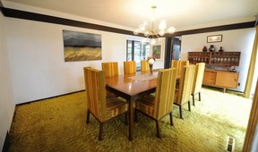 The formal dining room has shag carpet and a table designed by Thom.