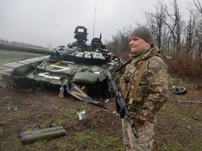 A Ukrainian service member stands next to a damaged Russian tank T-72 BV, as Russia's attack on Ukraine continues, in Donetsk region, Ukraine April 13, 2022.  REUTERS/Serhii Nuzhnenko/File Photo