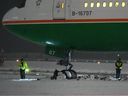 Workers are seen around an EVA Air Boeing 777 aircraft that went off a taxiway onto soft ground after landing at Vancouver International Airport from Taipei.