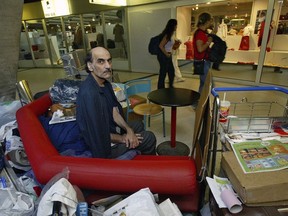 FILE - Merhan Karimi Nasseri sits among his belongings at Terminal 1 of Roissy Charles De Gaulle Airport, north of Paris on Aug. 11, 2004 . An Iranian man who lived for 18 years in Paris' Charles de Gaulle Airport and inspired the Steven Spielberg film "The Terminal" died Saturday, Nov. 12, 2022 in the airport, officials said. Merhan Karimi Nasseri died after a heart attack in the airport's terminal 2F around midday, according an official with the Paris airport authority. Police and then a medical team treated him but were not able to save him, the official said.