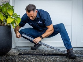 Home Inspector Paul Friesen of I Find It Inspections checks a gutter outside a garage door for potential blockages.