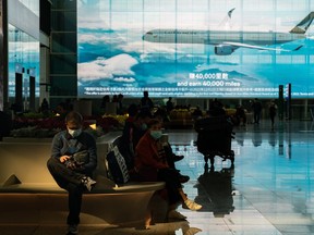 Travellers sit at the arrival hall of the Hong Kong International Airport on Dec. 30, 2022 in Hong Kong, China. Authorities around the world are imposing or considering curbs on travellers from China as COVID-19 case there surge following its relaxation of Zero-COVID rules.